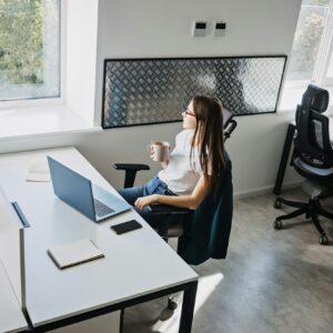 Businesswoman drinking coffee and resting in modern office. Good mental health at work