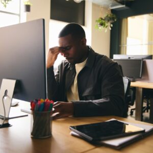 Stressed black businessman sat at office desk with mental illness